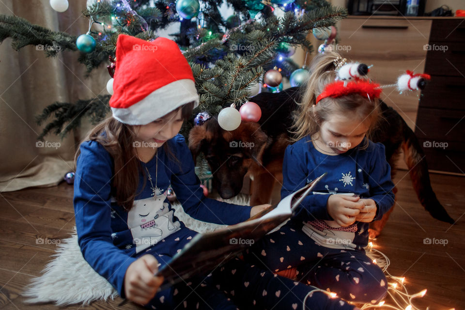 Little sisters reading a book at Christmas time 