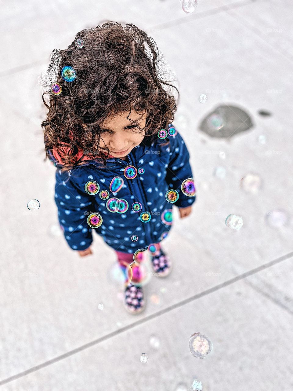 Little girl walks through a bunch of bubbles, bubbles are everywhere, circular bubbles and toddler, toddler girl loves bubbles, playing outside with bubbles, fun with bubbles, geometric shapes in everyday life