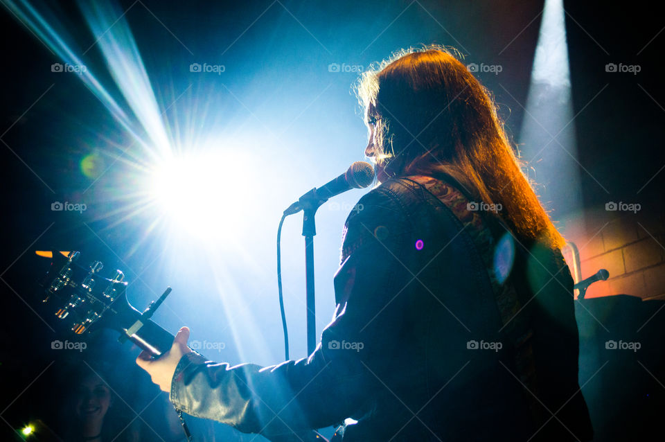 A woman singing and playing guitar on stage