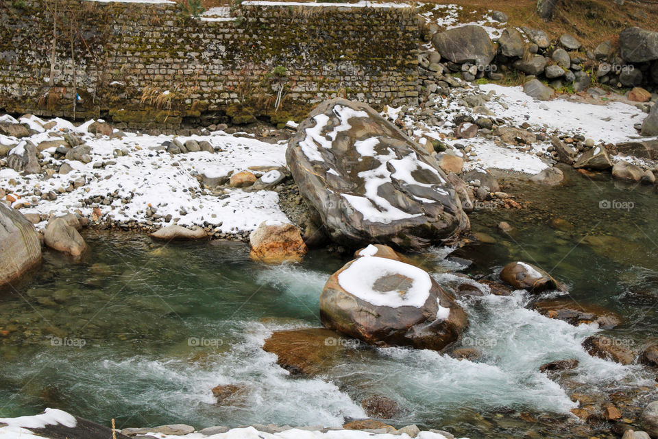 Snow on rocks with icy water