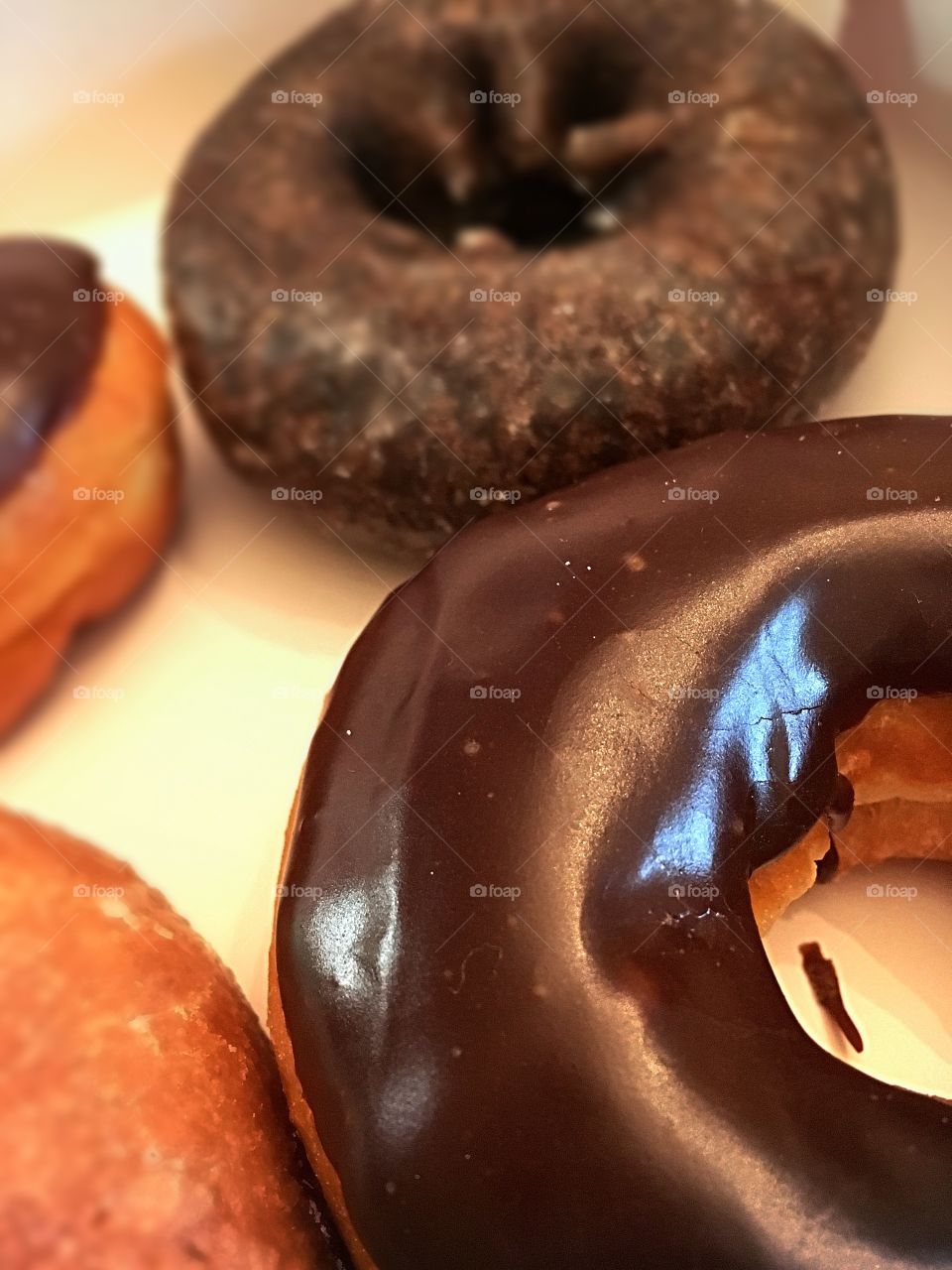 Focus on the foreground - box of donuts.  Chocolate, chocolate frosted, circular treats of deliciousness. 