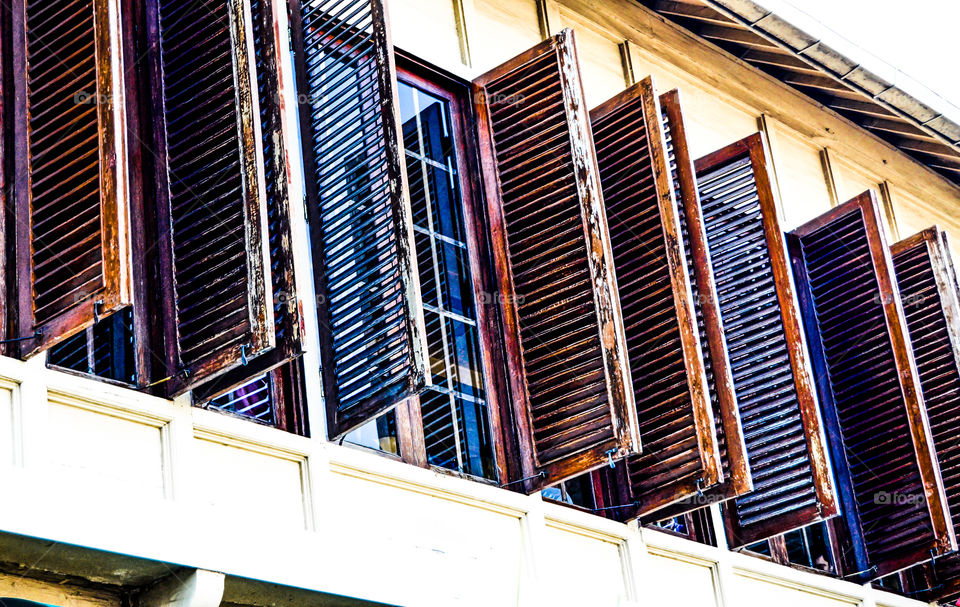 Rows of old windows of teak wood, wide open. An old Dutch heritage building in Indonesia