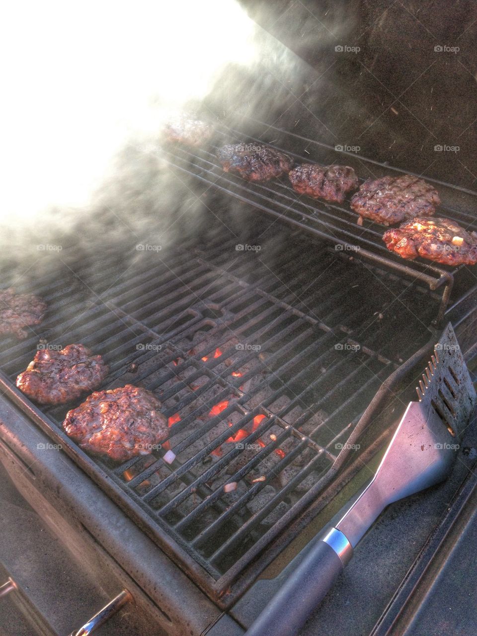 That great smoky taste. Hamburgers cooking in the grill and smoke rising 