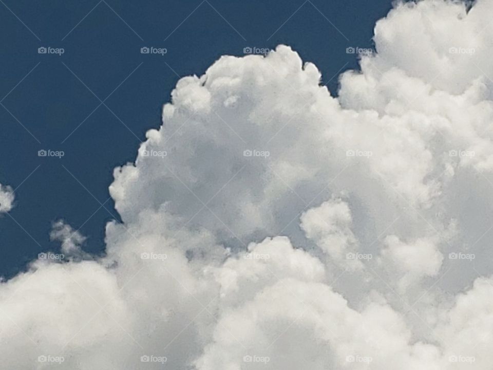 Fluffy cotton-like cumulus clouds adorn a clear blue sky