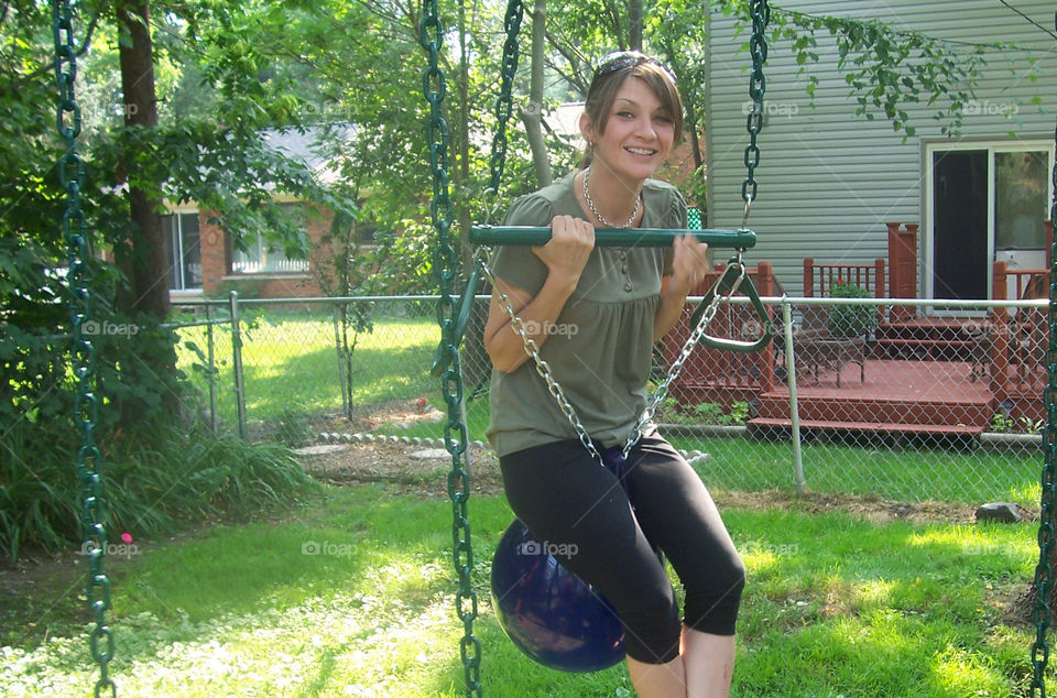 Still Got It. Young mother climbing on children's swing set. 