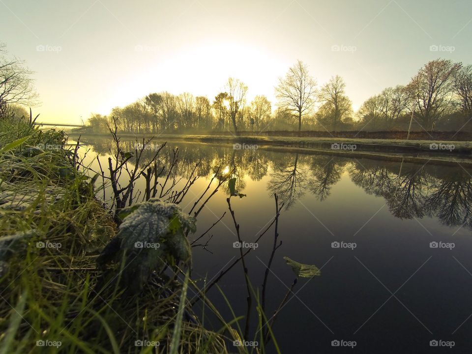 Countryside sunrise showing the colorful sky reflected in the water of the river 