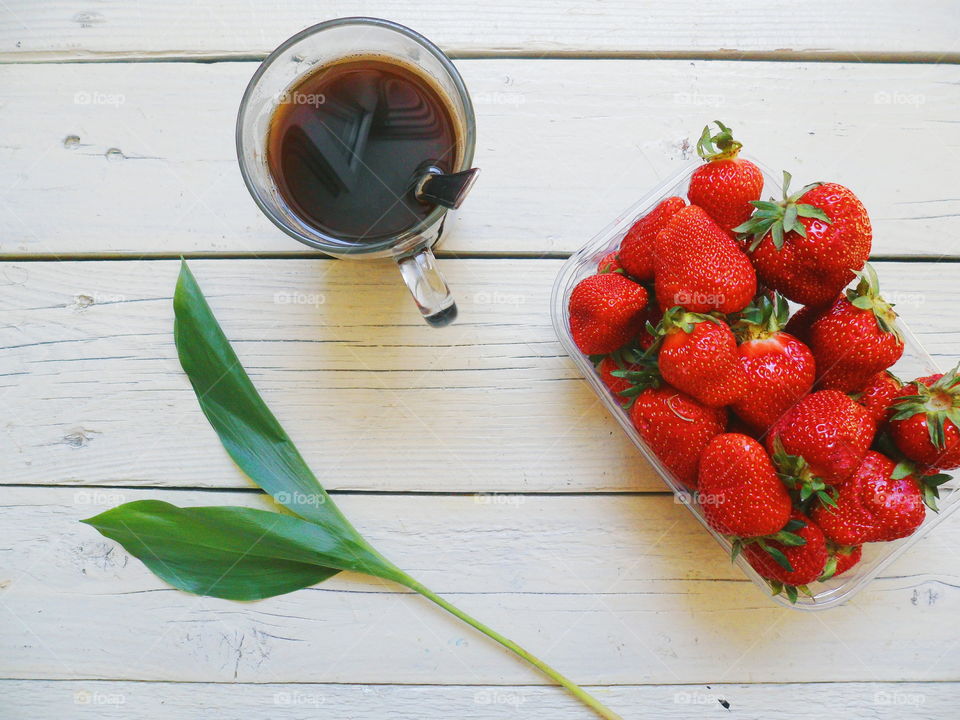 red strawberries, green leaf and coffee cup on white background