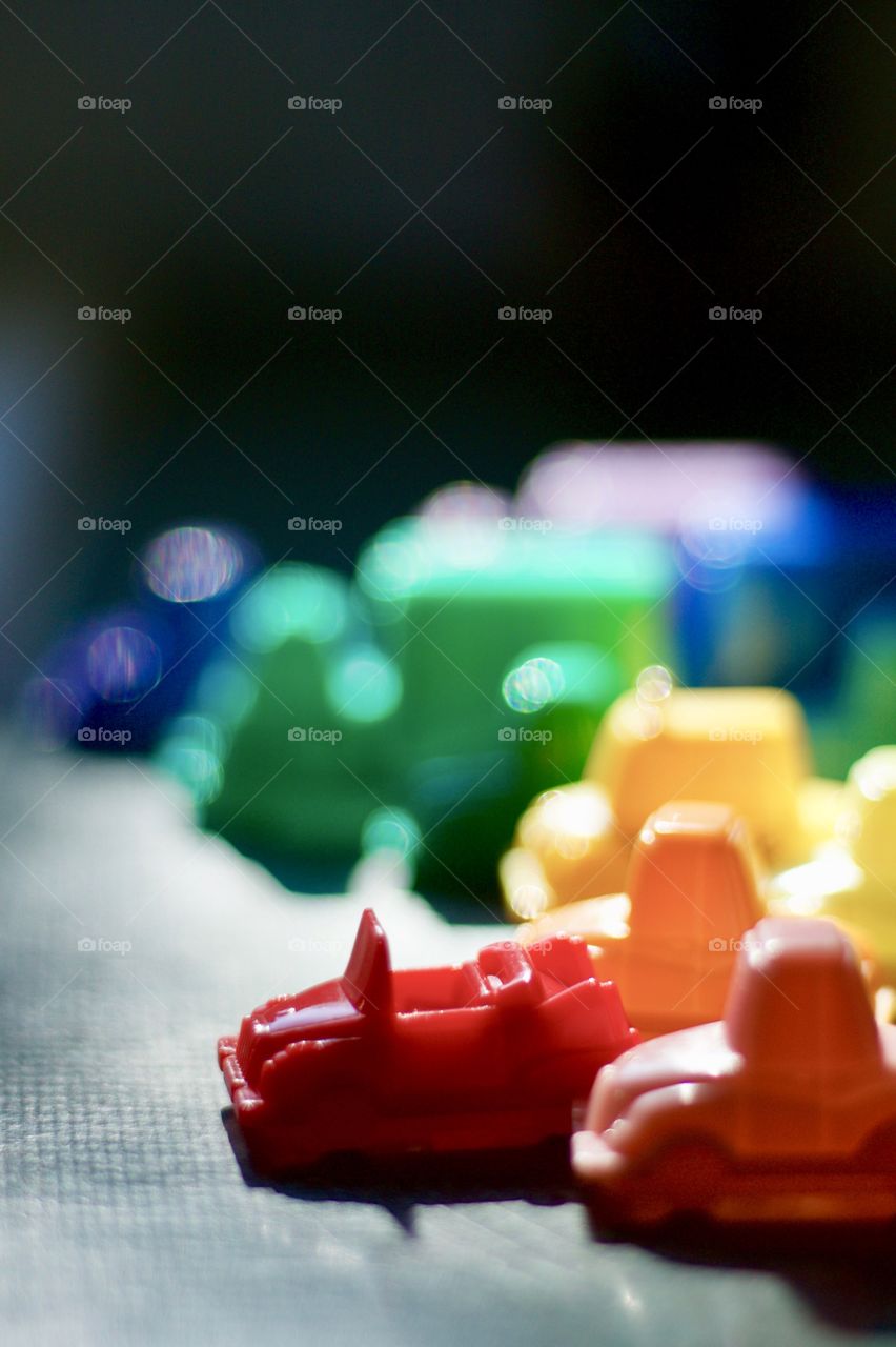 Color Love - low-angle, backlit view of a set of colorful, plastic, toy cars in pretend traffic 