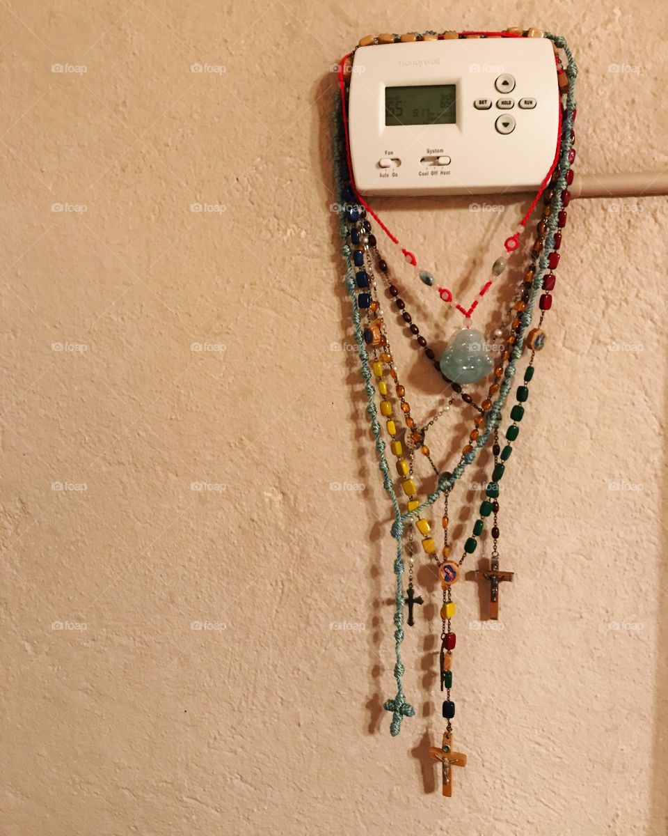 Rosaries hanging from a thermostat