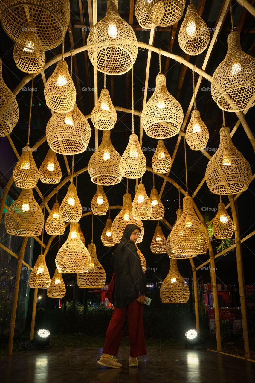 A veiled girl is standing above yellow lamp decorations