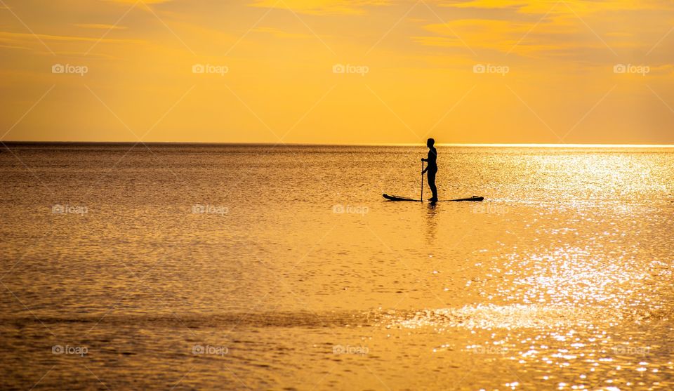 A paddle boarder at sunset