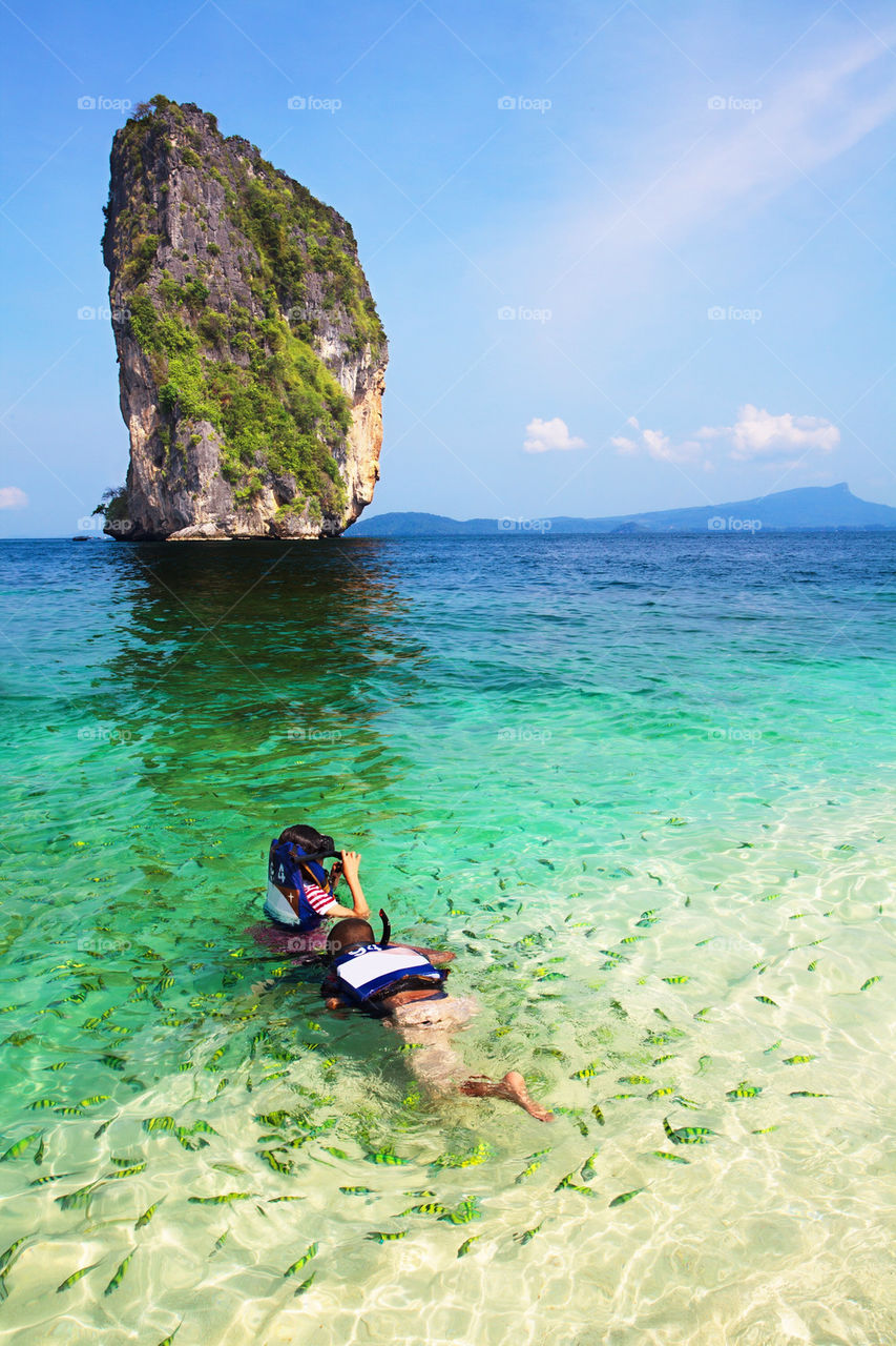 Kids being surrounded by fish while snorkeling