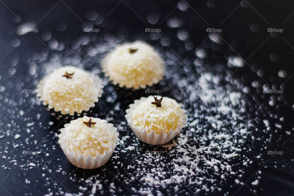 Four sweets made with condensed milk and shredded coconut, decorated with shredded coconut and cloves.