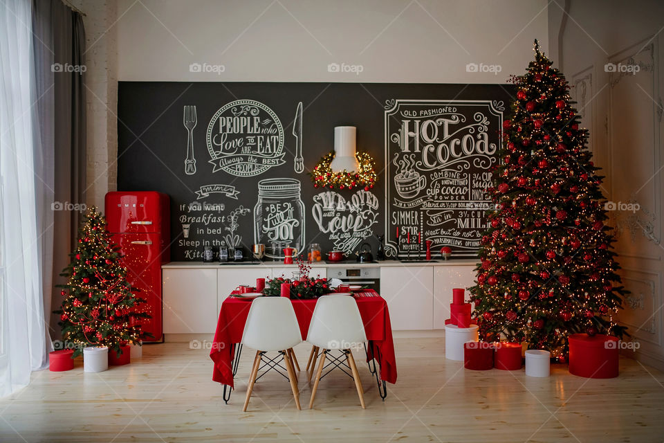 Festive winter cozy kitchen interior with garlands, decorations and gifts.  Christmas dinner at the decorated table.