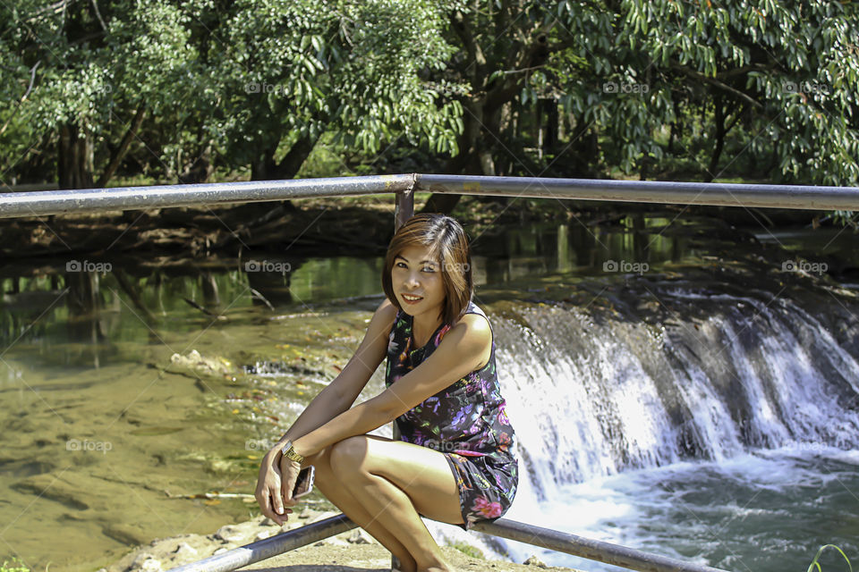 Asean woman and water in the stream is green and bright green tree at Kapo Waterfall Fores Park , Chumphon in Thailand.