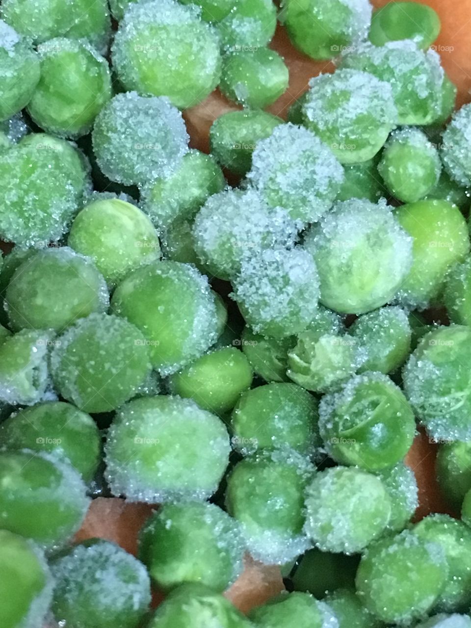 Close up view of green frozen peas with ice crystals on them in the kitchen before cooking 