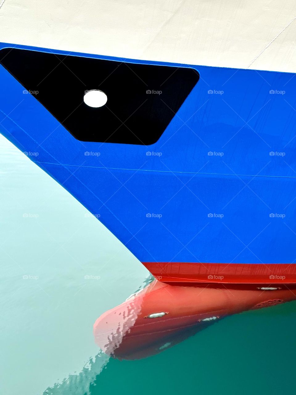 A red bulbous bow below the waterline on a blue ship with a white "eye".