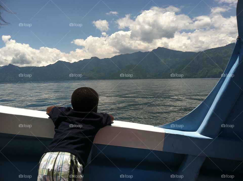 Contemplation. Boy admiring view of lake and landscape from boat