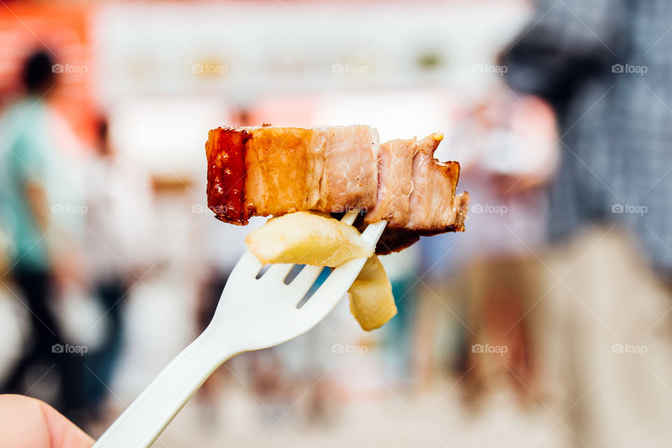 Bacon and French fry with a fork at street in summer festival.close-up