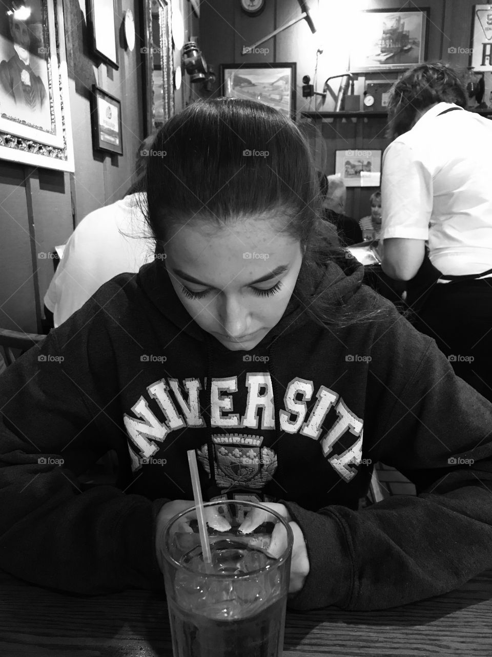 Teenage girl sitting in restaurant with cold drink on table