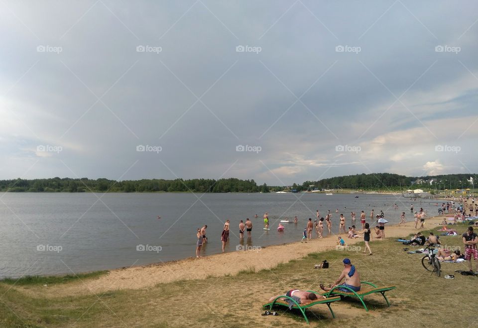 people resting on a lake shore summer time