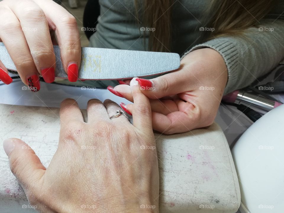 Beautician does a manicure to a client