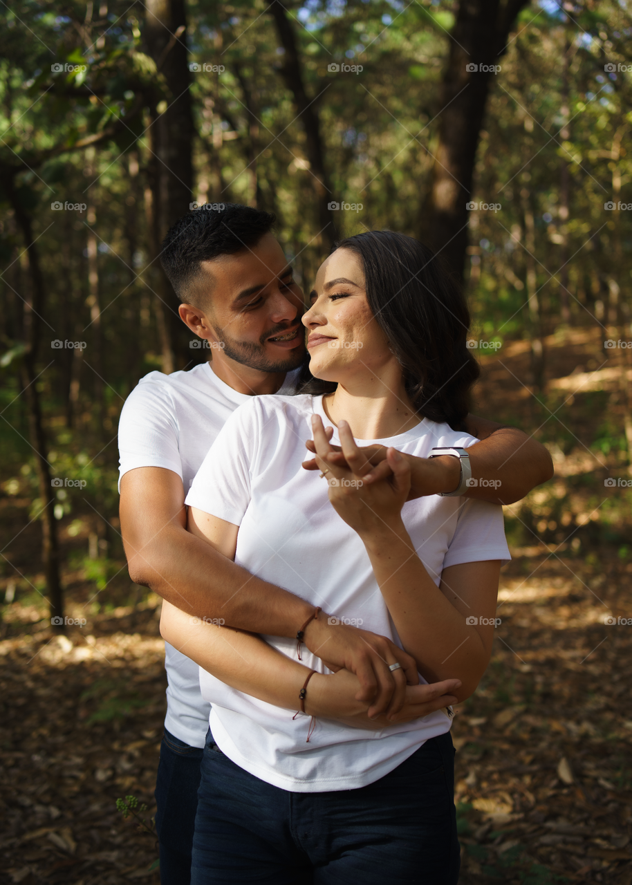 Couples of young people sitting in middle of the forest while looking into their eyes, in a sunny day.