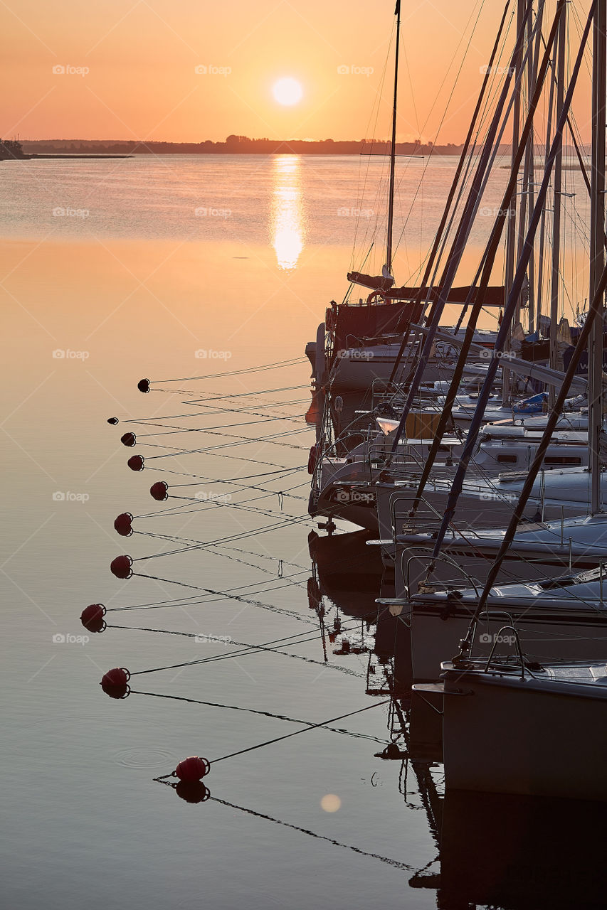 Yachts and boats moored in a harbour at sunrise. Candid people, real moments, authentic situations