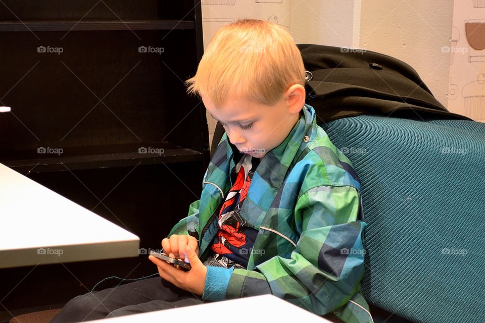 Boy using the phone at the coffeeshop