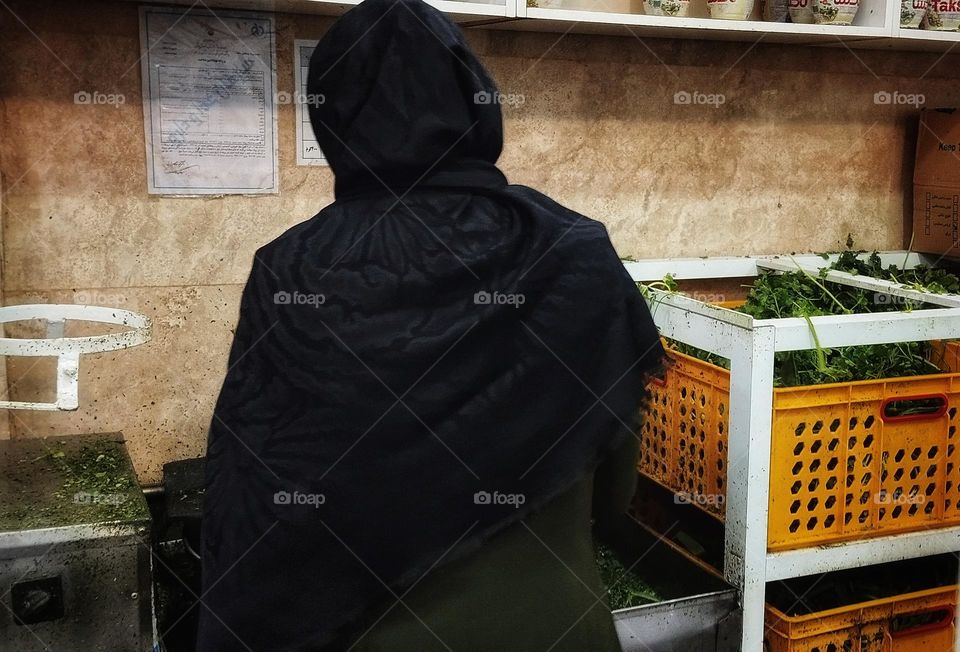 Well-behaved young girl is chopping different green vegetables .