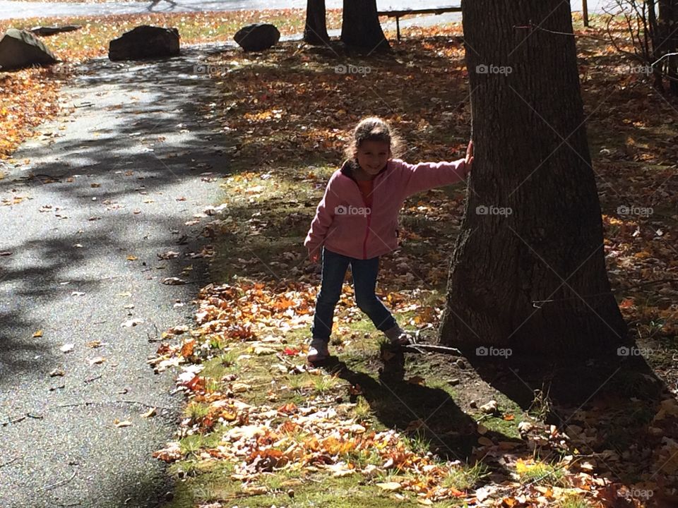 Girl child against tree in autumn foliage and sum shadow