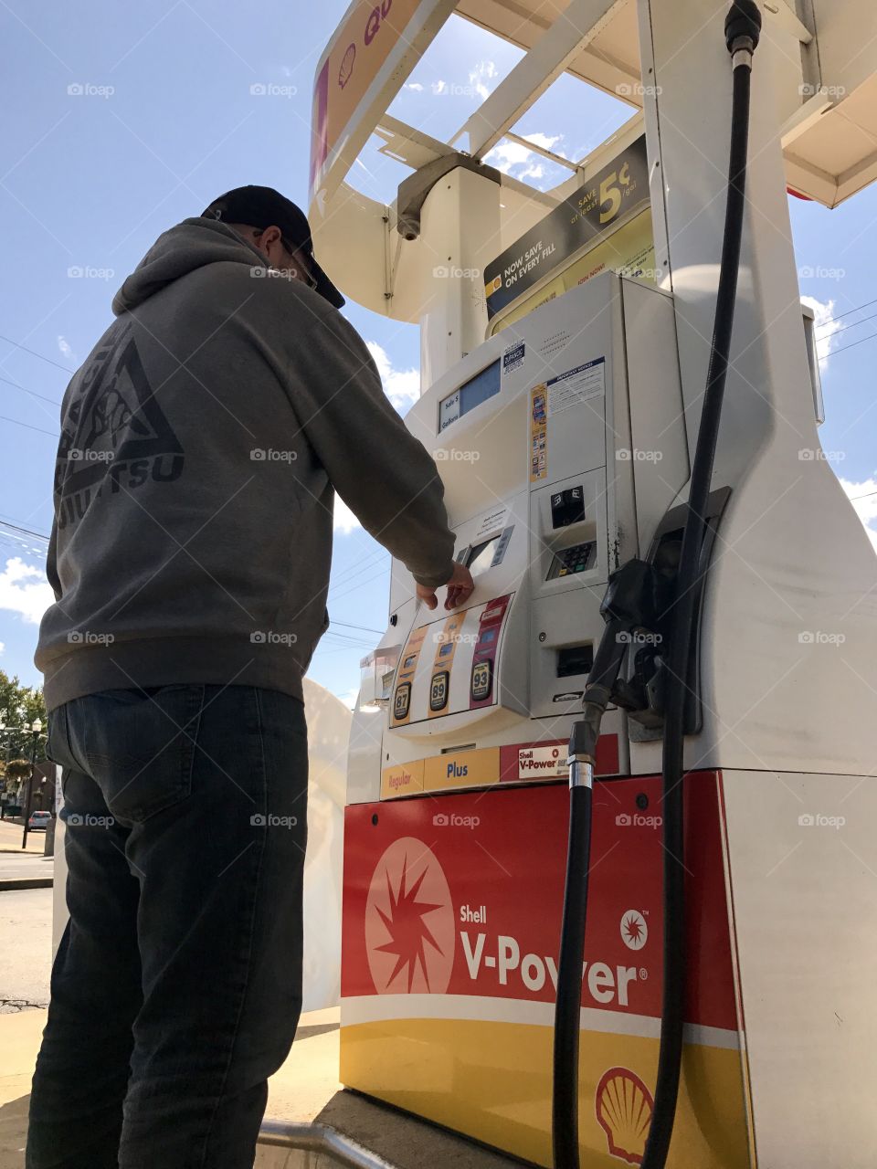 Man selecting grade of gas at Shell gas station during road trip 