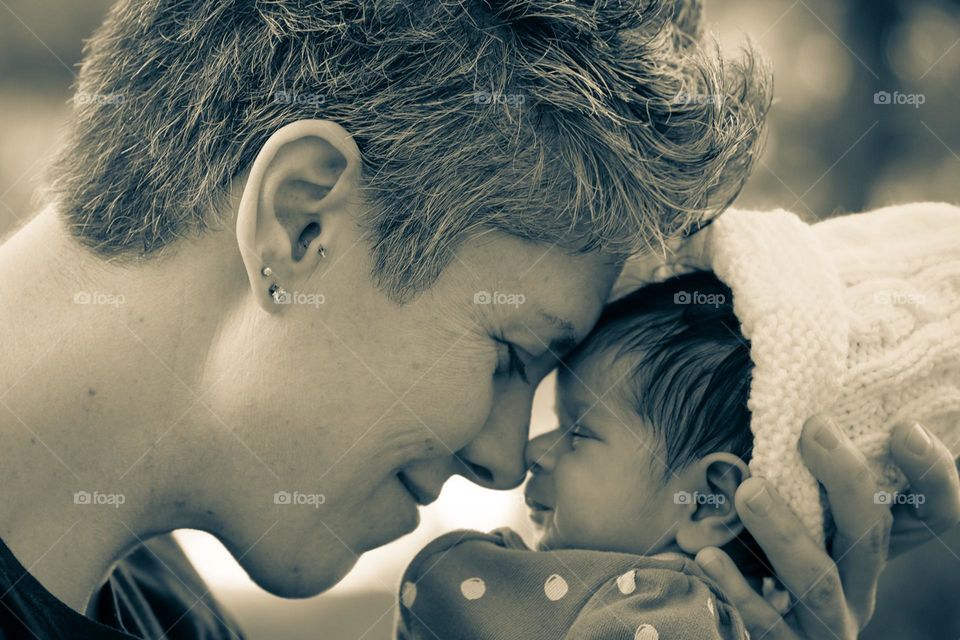 Mother smiles while holding newborn baby, mother is nose to nose with newborn baby, cute newborn baby photograph, sepia image of mother and daughter