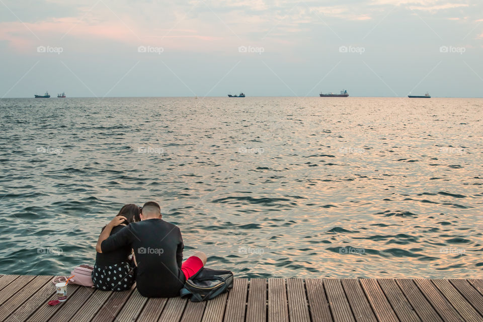 Couple In Love Sitting At The Dock Talking And Enjoying The View
