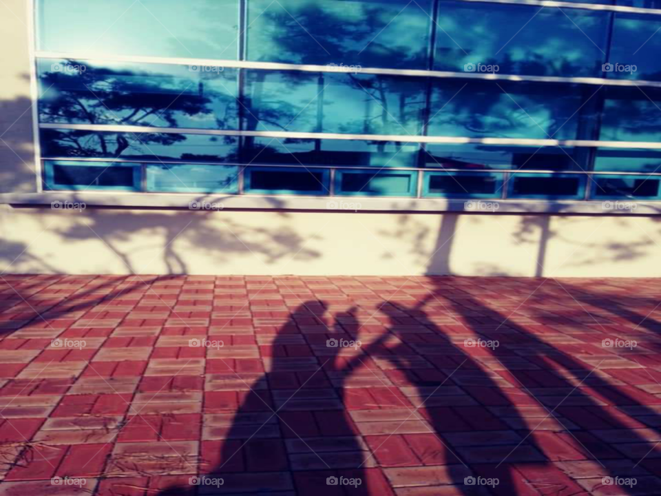 an mother and a child shadow. the mother is holding something and talking to the child. the child is facing her mother and listening.