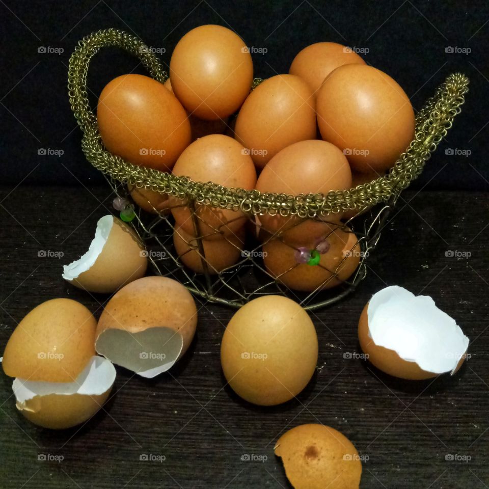 Eggs on the basket and cracked eggs on the table