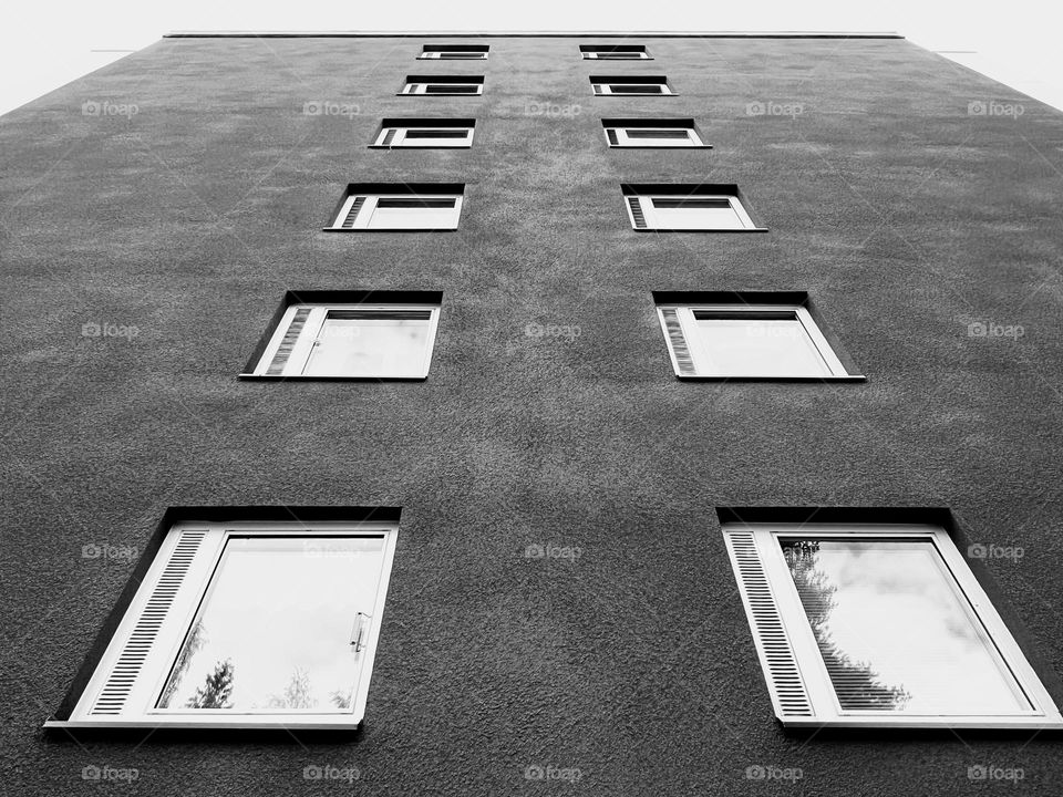 Black and white monochrome photo minimalistic modern architecture high building exterior wall with windows perspective bottom view