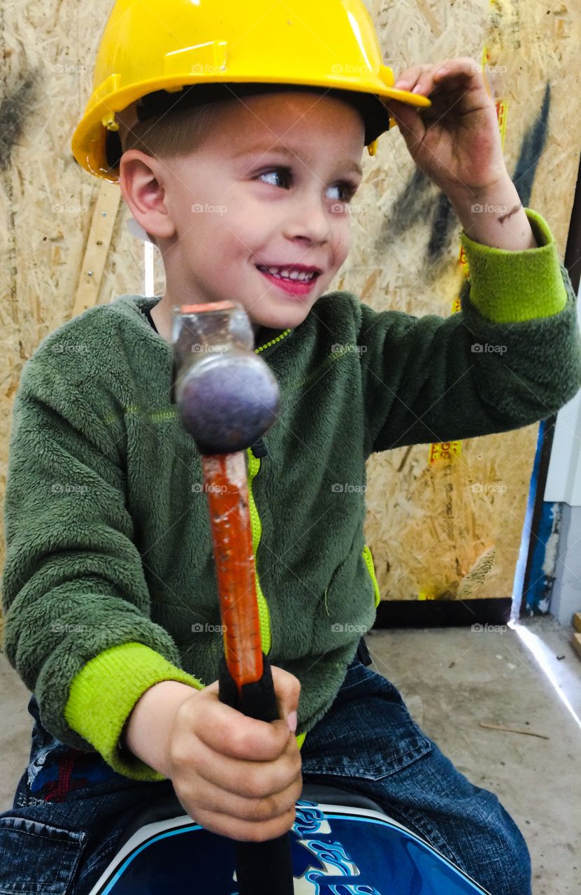 Boy with hammer. A boy is helping out at his fathers work