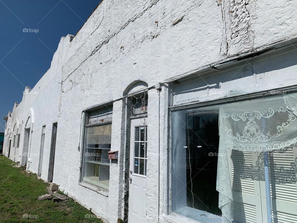 Old white architectural building with signs of aging elements under a blue sky in the afternoon.