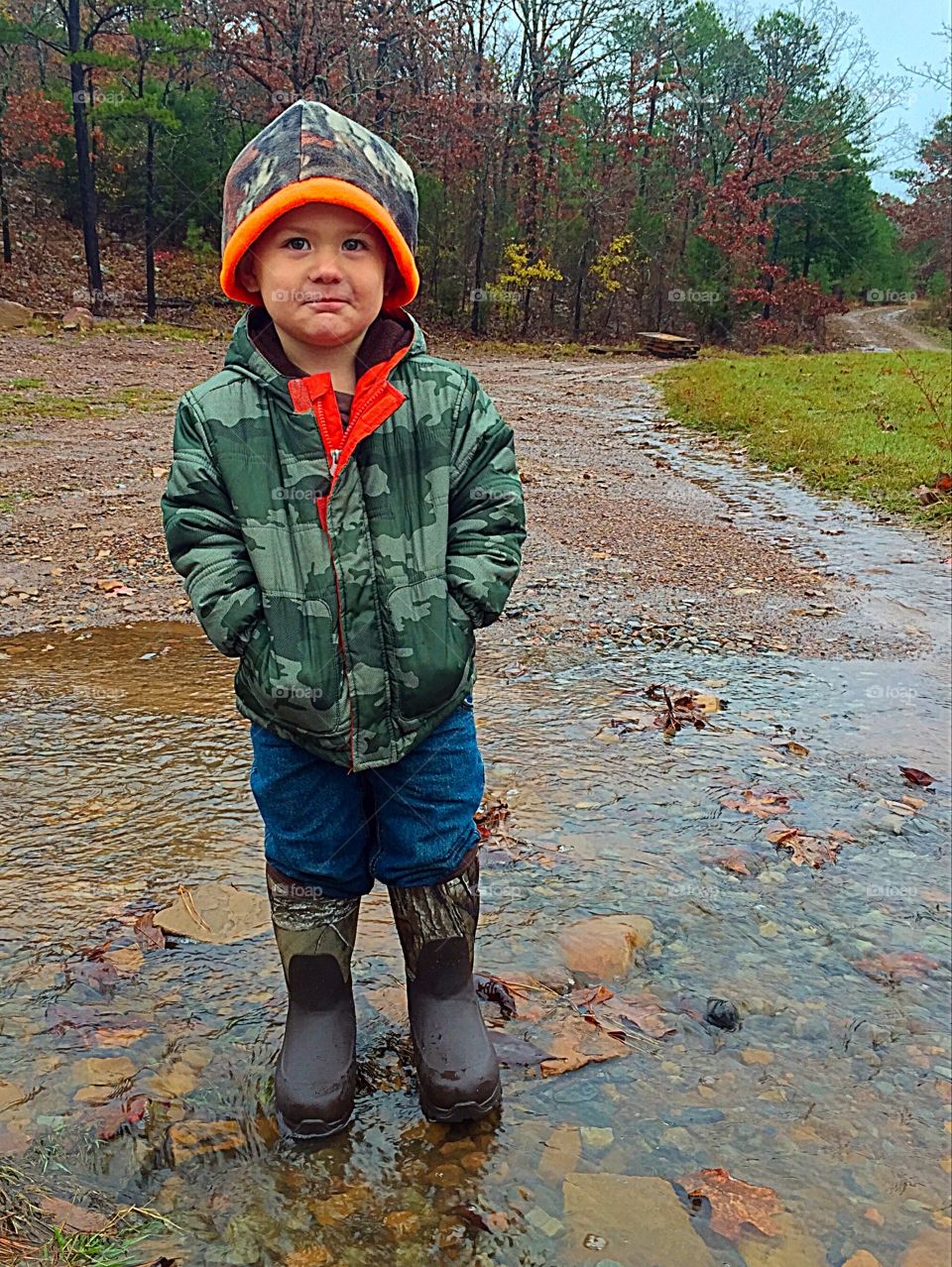 Boy child playing in road puddles