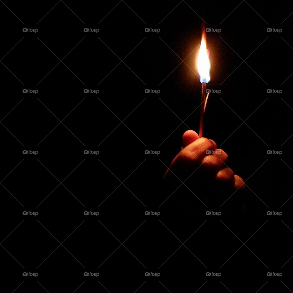 A flame from a match being held in the dark