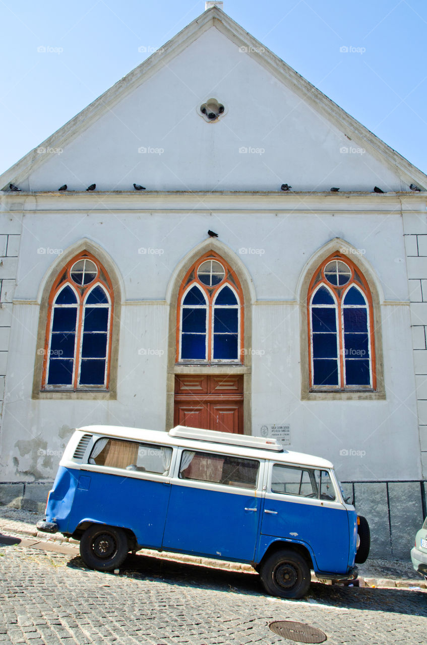 A vintage Volkswagen camper van parked in a sloping street in Lisbon, Portugal