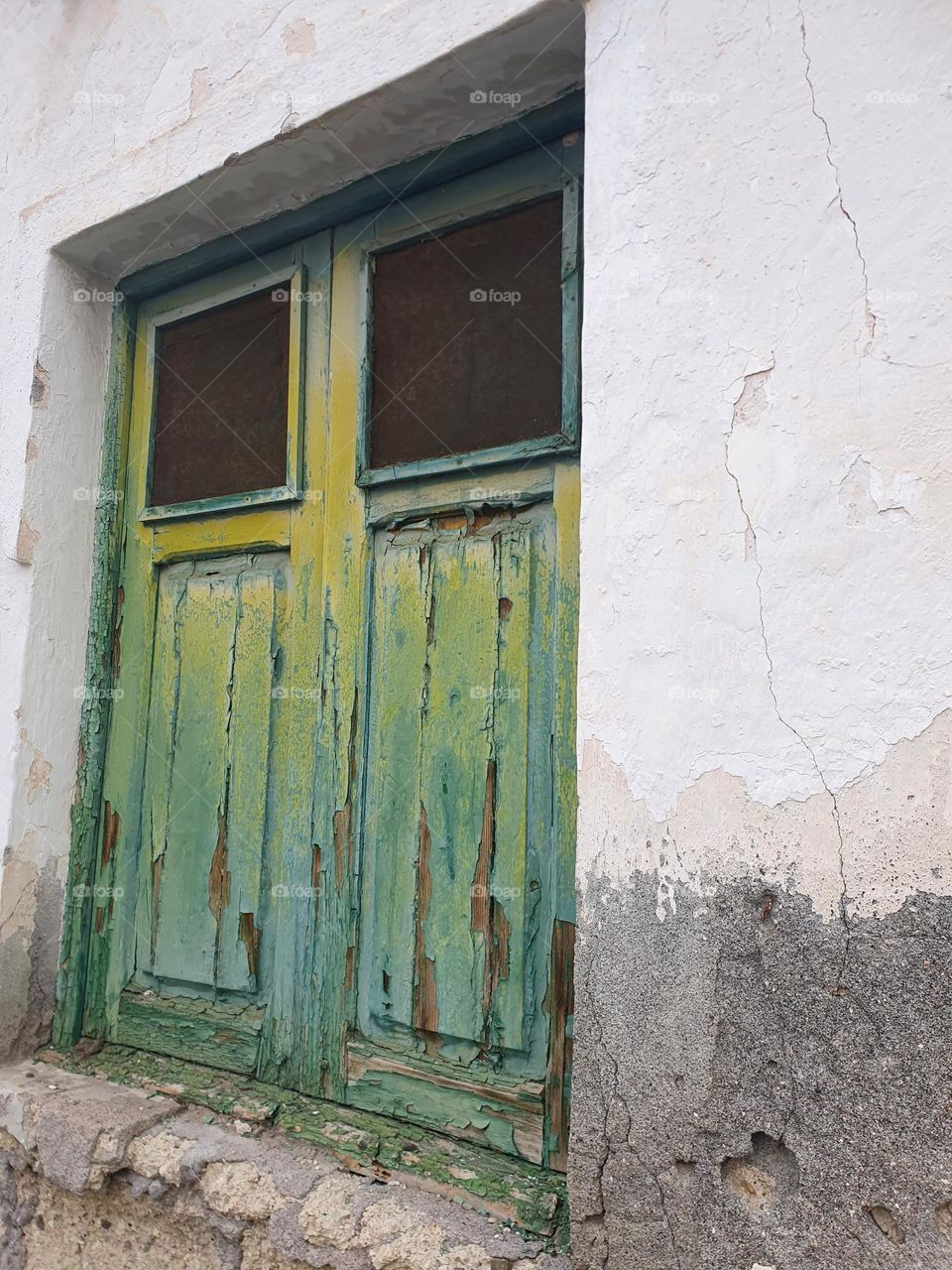 green - dilapidated house wall with green peeling paint on a wooden window