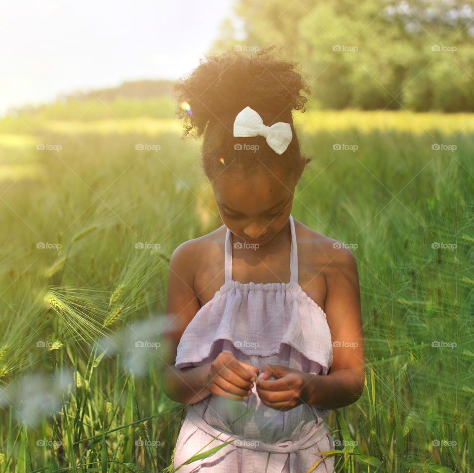 Girl of mixed race walking outdoors in barley fields during summertime