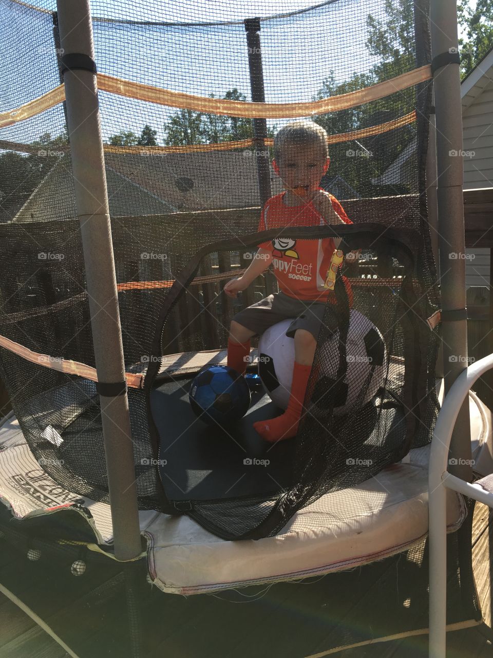 Little boy eating ice lolly in trampoline