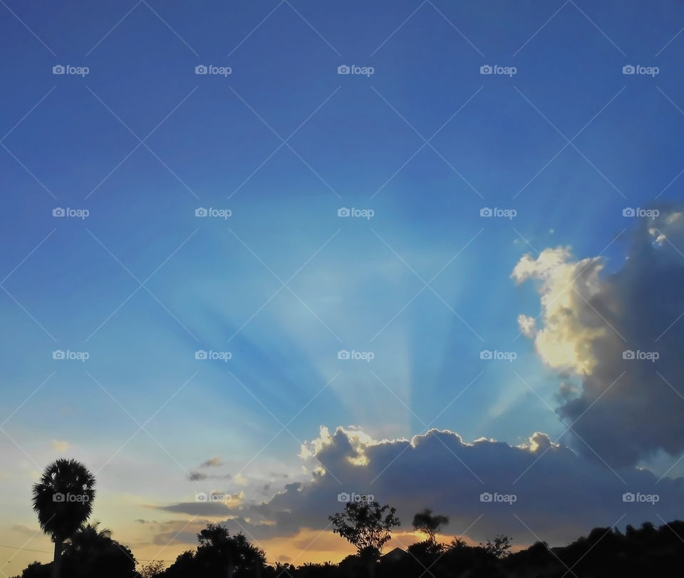 Evening Sun Rays Emerging From Beneath The Clouds