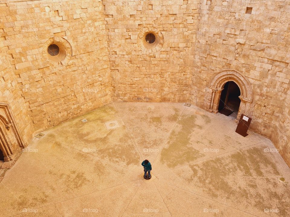 person in the center of the octagonal courtyard of the ancient castle