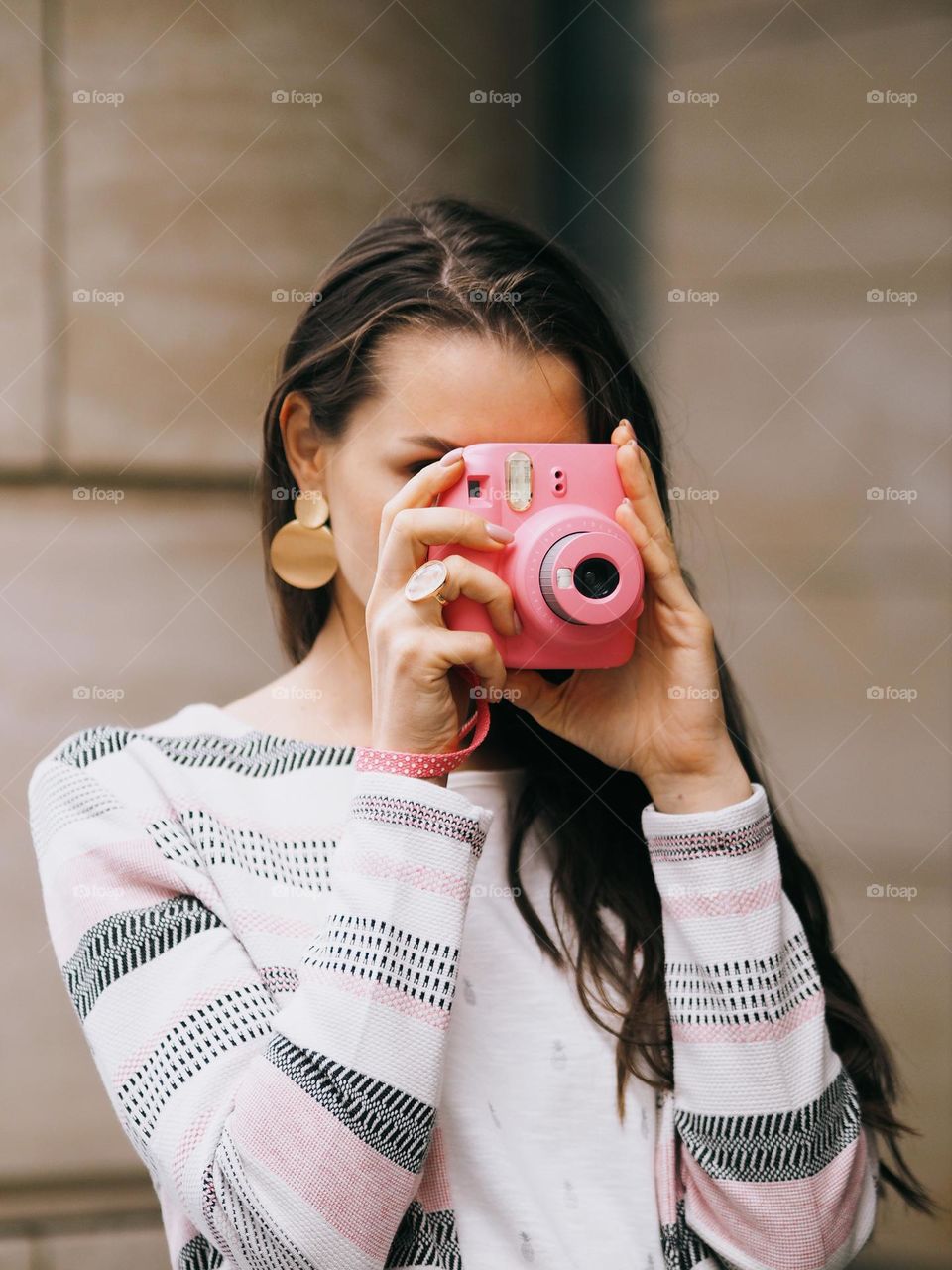 Young beautiful girl with dark long hair is taking pictures walking through the city on a summer day, portrait of woman 