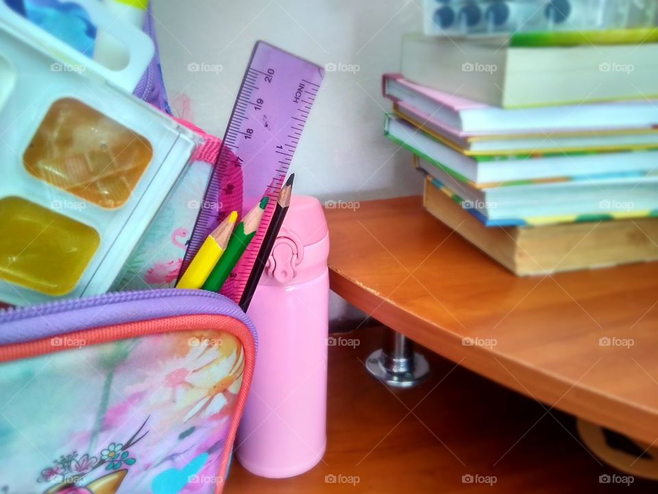 collection of school supplies in a backpack, books lying on the table and a student's thermo mug