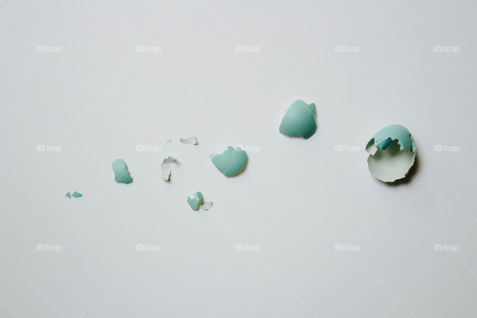 Minimal flat lay of a broken robin’s egg on white background in natural light